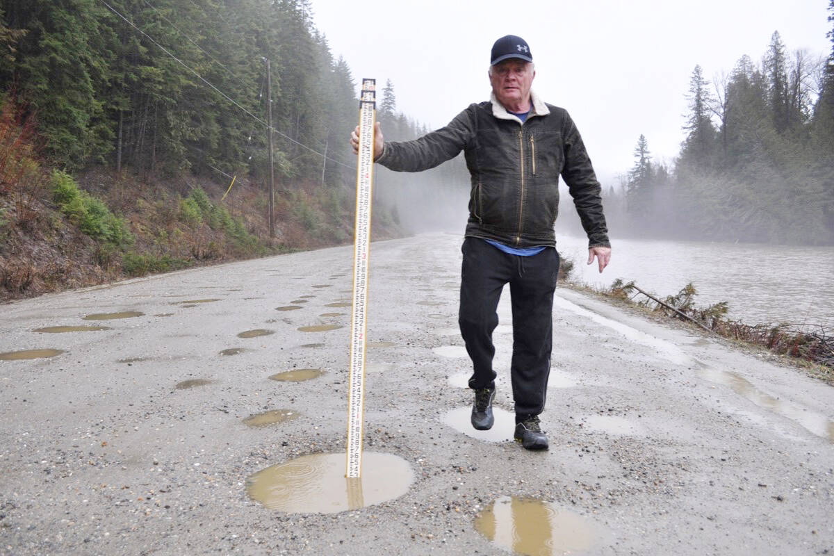 Grant Trower measures a pothole, some of which are as deep as six inches. (Tyler Harper/Nelson Star)