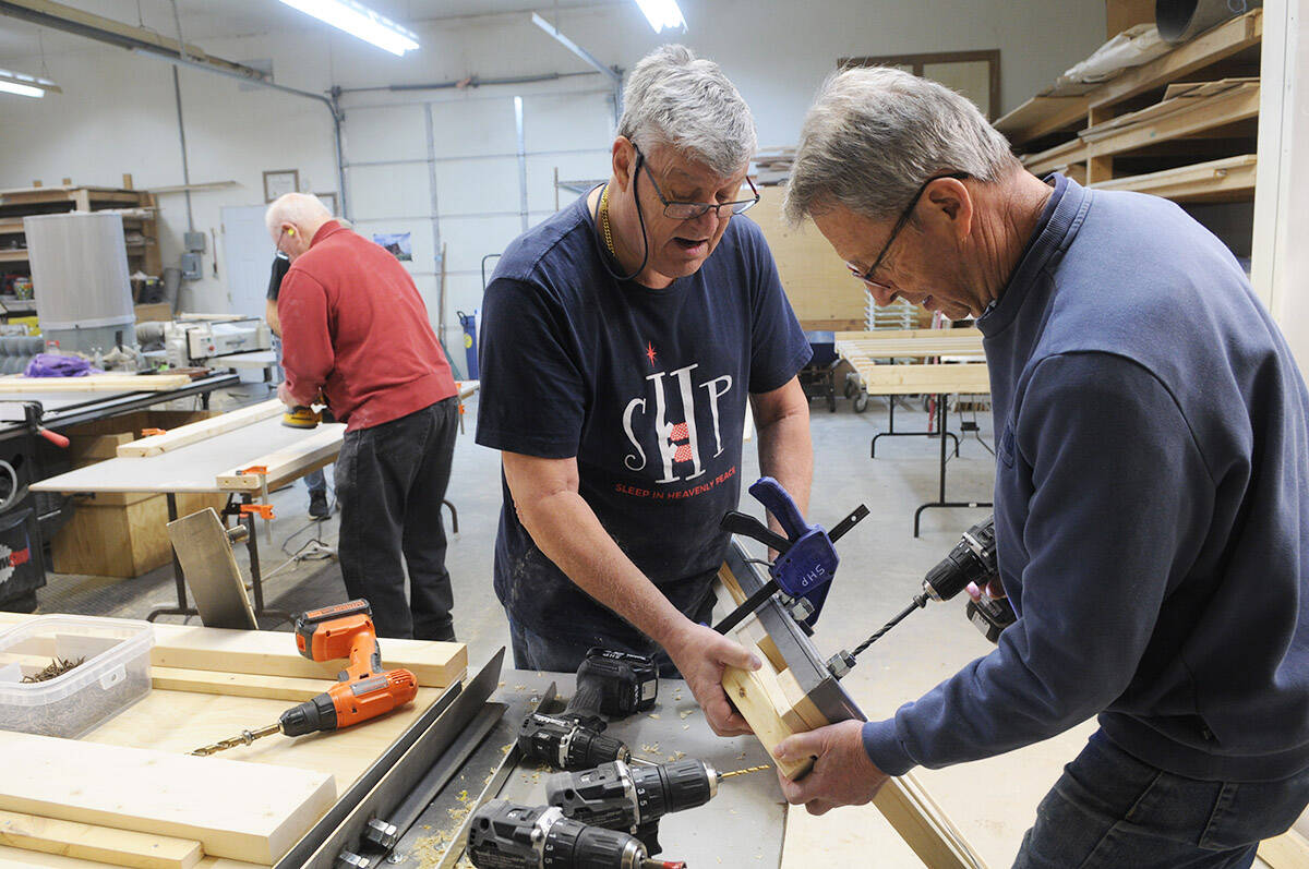 Ernie Block (left) and Phil Dueck drill a hole into a bed frame while volunteering with Sleep in Heavenly Peace on March 21, 2026. (Jenna Hauck/ Chilliwack Progress)